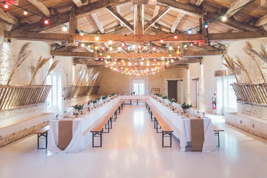 A rustic wedding reception hall with long tables and wooden benches