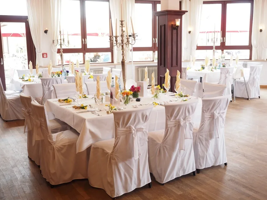 Wedding reception tables laid with white chair covers and candles