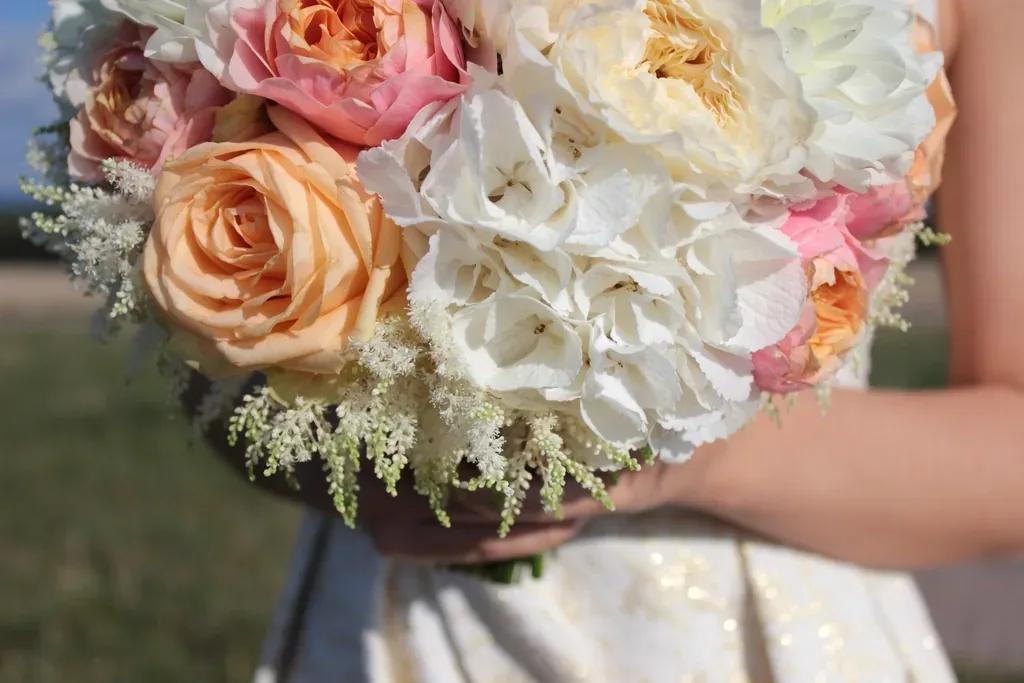 A bride holding a bouquet of roses and hydrangeas