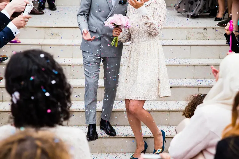 Newlyweds walking down the steps while guests shower them with confetti
