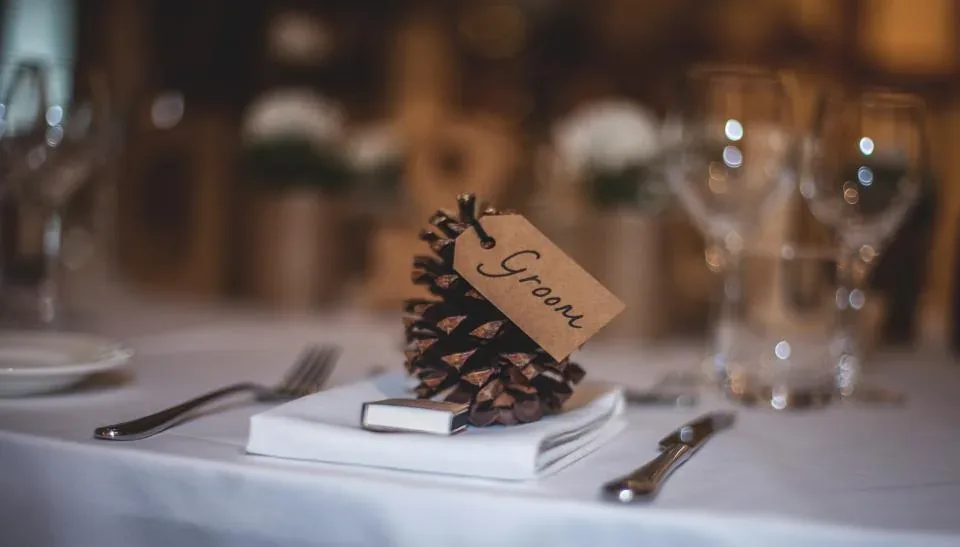 A place card on a pine cone at a wedding table setting