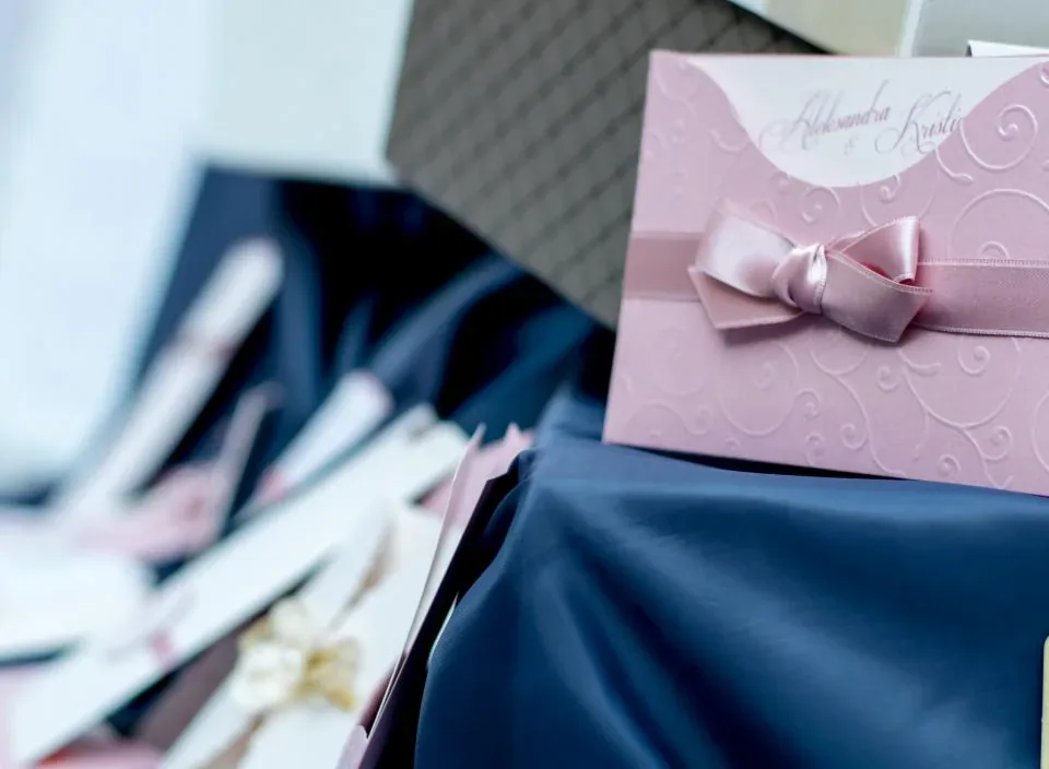 A pink wedding invitation tied with a ribbon