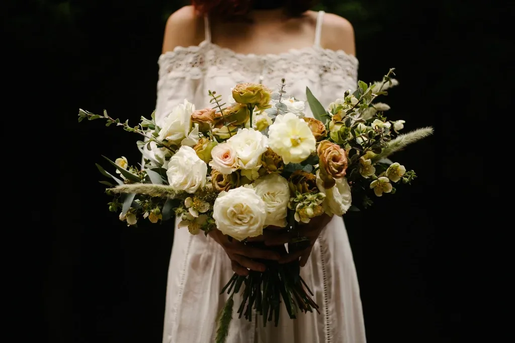A bride holding a bouquet of white and peach roses